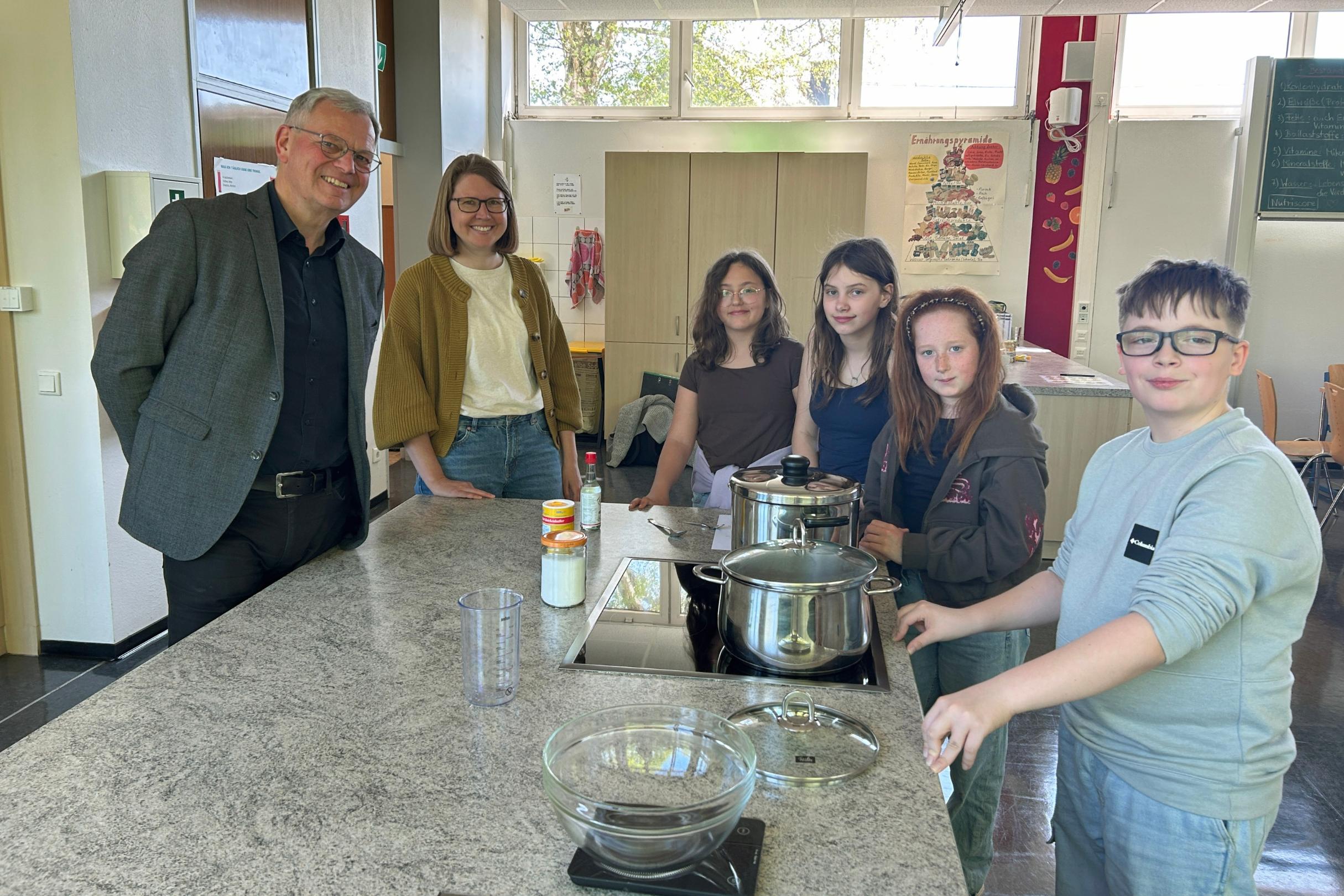 Bischofsvikar Ulrich von Plettenberg, Pastoralreferentin Carina Rui, Vivienne, Vivien, Mailin und Kay kochen den Reis für die Sushi-Bowls.